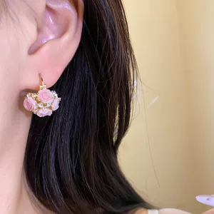 Vue rapprochée d'élégantes boucles d'oreilles panier de fleurs en résine rose et strass