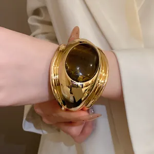 Close-up detail of vintage gold cuff bracelet featuring a large oval tiger eye stone inlay