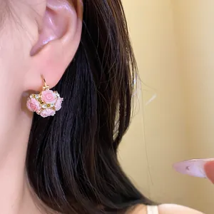 Gros plan sur des boucles d'oreilles panier de fleurs roses en résine avec strass
