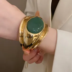 Detailed view of a vintage gold cuff bracelet featuring a large oval green stone