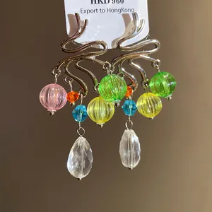 Dettaglio di orecchini pendenti in argento con perle di vetro colorate e gocce sfaccettate