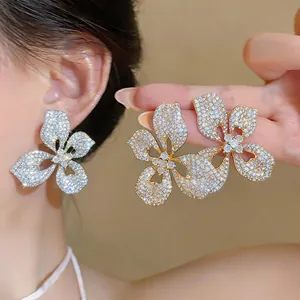 Close-up of large floral stud earrings with pavé set crystals for elegant bridal wear.