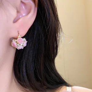 Détail en gros plan de boucles d'oreilles créoles panier fleuri en résine rose avec strass