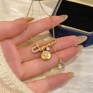 Detailed view of an 18K gold-plated safety pin necklace with star and zircon charms