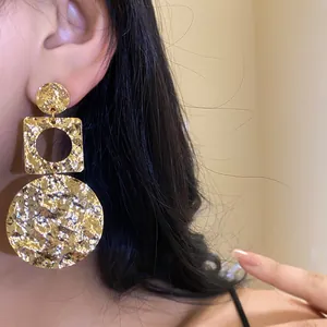 Detailansicht eines Modells mit strukturierten goldenen Ohrringen im Vintage-Design