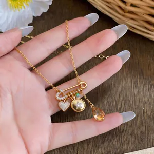 Close-up of 18K gold-plated necklace with heart, star charms and orange teardrop bead