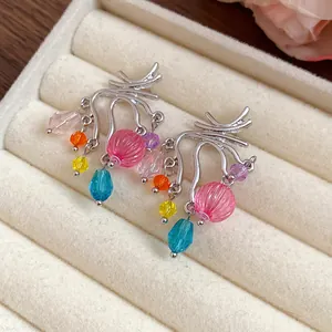 Dettaglio di orecchini geometrici in argento con nappe di perline colorate in vetro