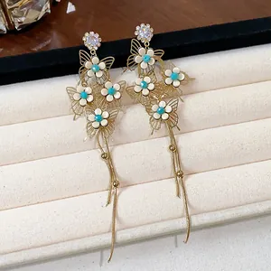 Detailed close-up of French style butterfly flower earrings with long elegant gold tassels