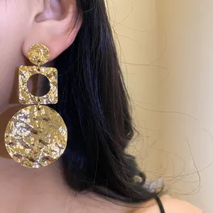 Nahaufnahme von 18k vergoldeten, gehämmerten geometrischen Hängeohrringen im Vintage-Stil