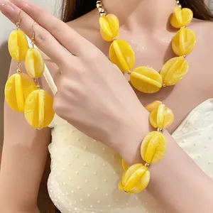 Detailed view of yellow marbled acrylic bead necklace, bracelet and earrings on model