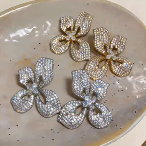 Macro view of sparkling four-petal flower stud earrings in gold and silver finishes