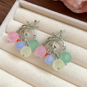Dettaglio di orecchini a nappa con perle di resina colorata in un portagioie di velluto