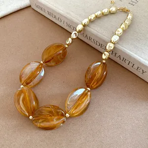 Detailed macro view of amber marbled acrylic beads and shiny gold-toned metal necklace