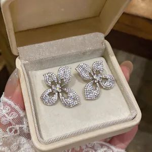 Macro view of sparkling four-petal flower stud earrings with intricate stone pavé detail