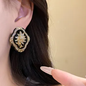 Close-up of a vintage floral earring with gold and rhinestones on black enamel.