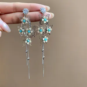 Detailed view of elegant silver needle earrings with butterfly and flower tassel design.