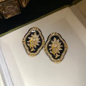 Close-up view of vintage gold floral stud earrings with clear crystals on black resin.