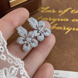 Detail view of sparkling five-petal flower earrings with micro-pavé crystals