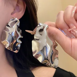 Elegant large geometric crumpled silver stud earrings with a high-shine metallic finish