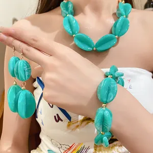 Close-up of turquoise marble acrylic beaded necklace, bracelet and earrings set on a model.