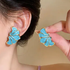 Detail showing elegant blue enamel flower earrings with gold finish and silver pins