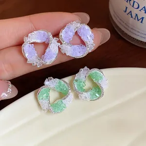 Detailed macro shot of elegant silver vortex stud earrings with purple and green crystals