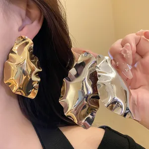 Macro detail of oversized metallic gold and silver crinkled geometric stud earrings
