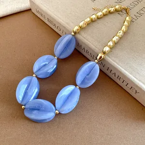 Macro detail view of chunky blue marbled acrylic beads and gold-tone necklace chain