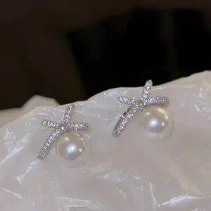 Detail view of elegant bow-shaped earrings with sparkling crystals and white pearls.