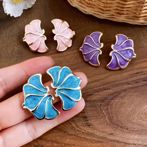 Macro detail of elegant enamel flower earrings in blue, pink, and purple with gold trim