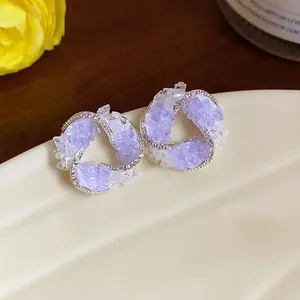 Macro view of purple crystal glass vortex stud earrings with sparkling zircon accents