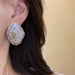Elegant vintage court style rhinestone flower earrings with silver needles shown on ear