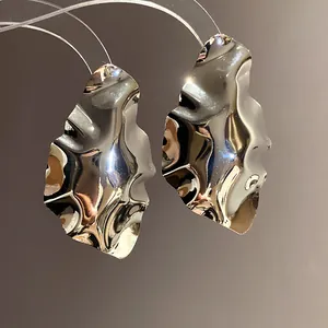Macro detail of silver geometric wrinkled earrings with polished metallic surface