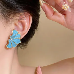 Elegant French style blue enamel flower stud earring with gold border worn on the ear