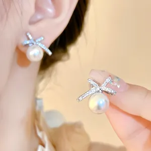 Detail view of dainty bow-shaped earrings with large white pearl drops