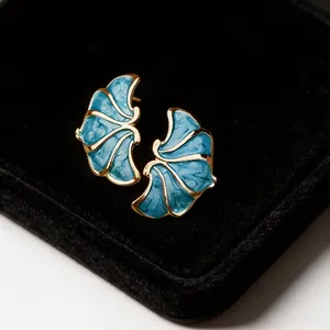 Detailed macro view of elegant French style blue enamel flower earrings with gold finish.