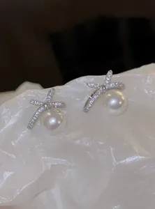 Close-up detail of elegant pearl bow earrings featuring sparkling crystal-encrusted ribbons
