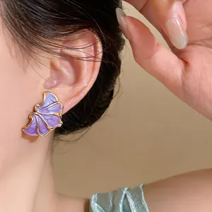 Elegant close-up view of purple petal-shaped drip oil earrings with golden trim details.