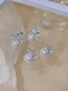 Detailed view of elegant pearl stud earrings with sparkling rhinestone bow design.