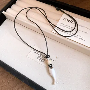 Dettaglio di una collana con ciondolo a forma di pesce in ceramica retrò e cuoio