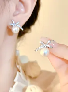 Detailed view of elegant silver bow-knot earrings featuring a lustrous pearl drop