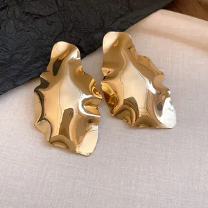 Macro detail showing the geometric crumpled texture of these elegant gold polished earrings