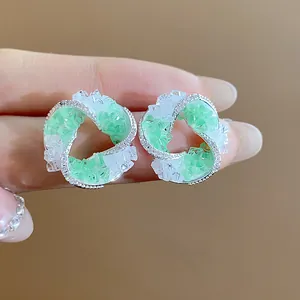 Detailed macro view of unique swirl stud earrings with green and clear crushed glass chips