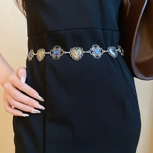 Close-up of vintage heart and flower metal chain belt with blue accents on black dress.