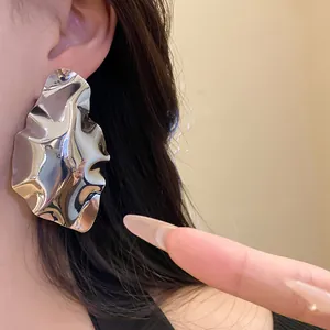 Macro detail view of a large geometric crumpled silver earring with a polished finish