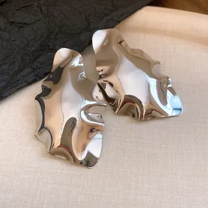 Macro view of silver irregular crumpled geometric earrings with high-gloss metallic finish