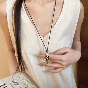 Collana retrò in cordoncino di cuoio con pendente a forma di pesce indossata da una modella.
