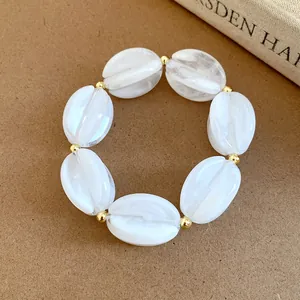 Close-up detail of white marbled acrylic beads and gold spacers on a chic jewelry piece