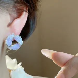 Detail view of elegant purple swirl stud earrings with silver pin worn by model