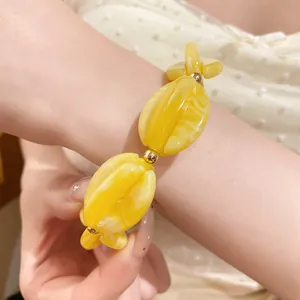 Detailed macro view of yellow marbled acrylic beads on a chunky fashion bracelet.